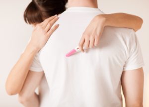 Close up of woman with pregnancy test hugging man